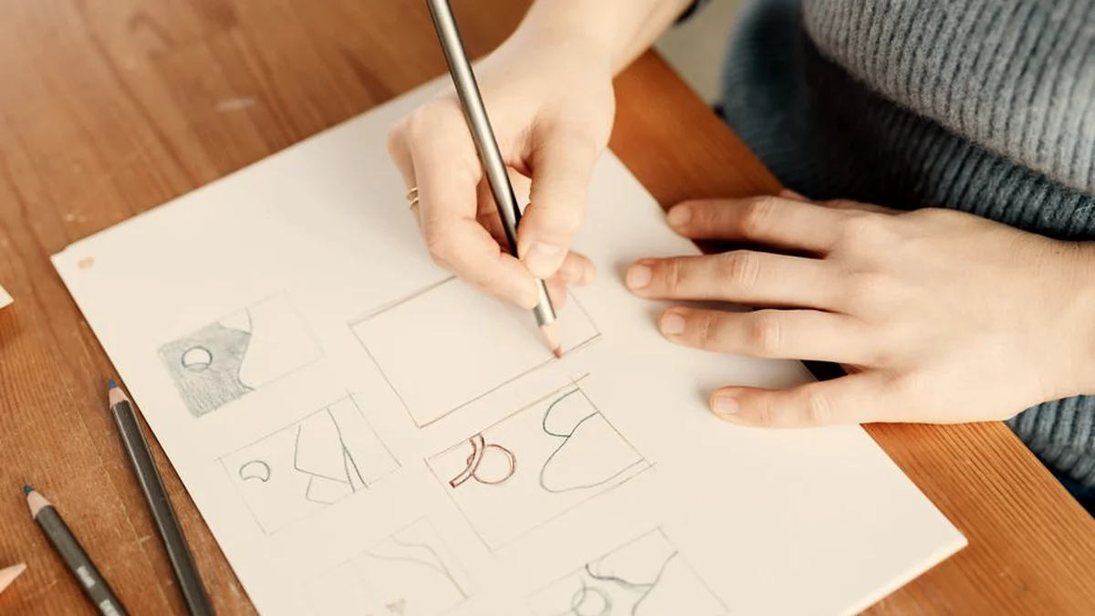 Main qui trace un schéma au crayon sur une feuille blanche