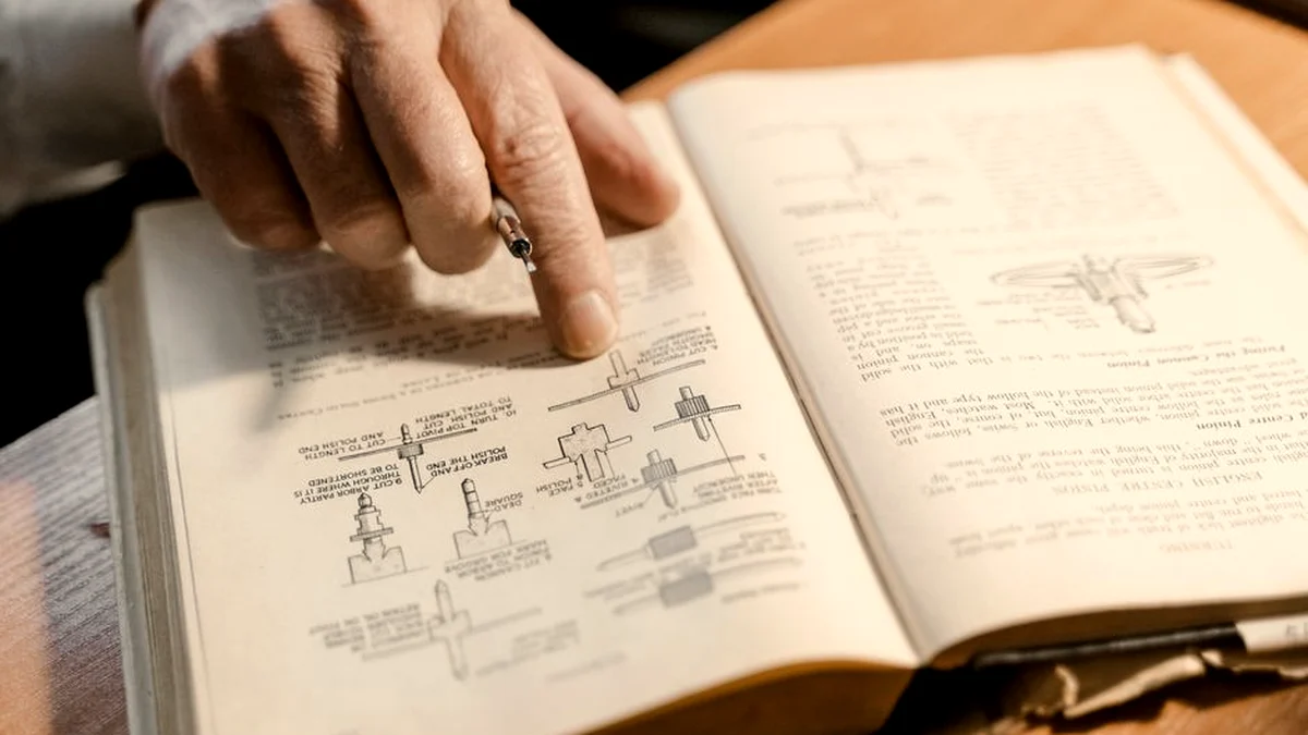 Main qui tourne la page d'un manuel technique ouvert