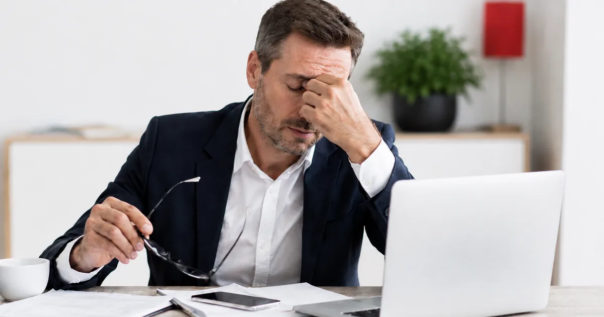 Dirigeant de PME seul dans un bureau devant une annonce de recrutement pour un poste administratif, illustrant le cycle recruter, former, voir partir.